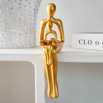 Goldene Harzskulptur „Eltern-Kind beim Lesen“