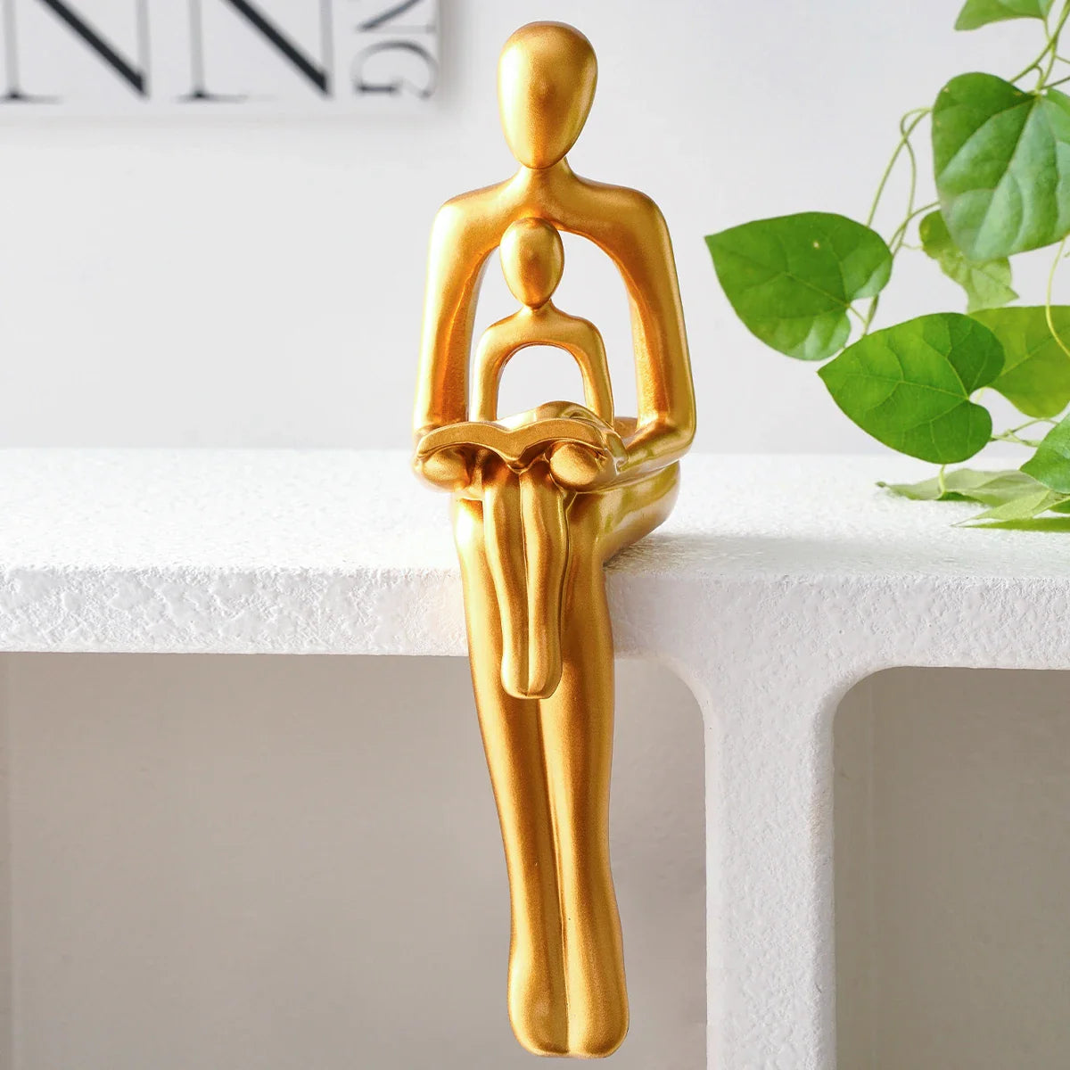 Goldene Harzskulptur „Eltern-Kind beim Lesen“